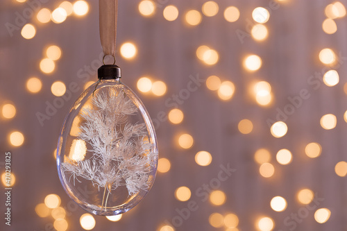 Hanging Christmas Glass bauble filled dried flowers, grass. Botanical Christmas ornaments with blurred bokeh background. Design transparent ball for New Year or xmas treey photo