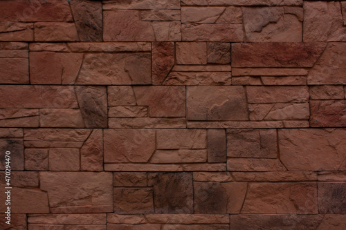Dark red wall of old brick close-up. Brick texture made of uneven elements. 