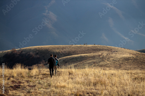 Two young men hiking and trekking over rolling meadows of Stara planina in late autumn afternoon sun © Ivan