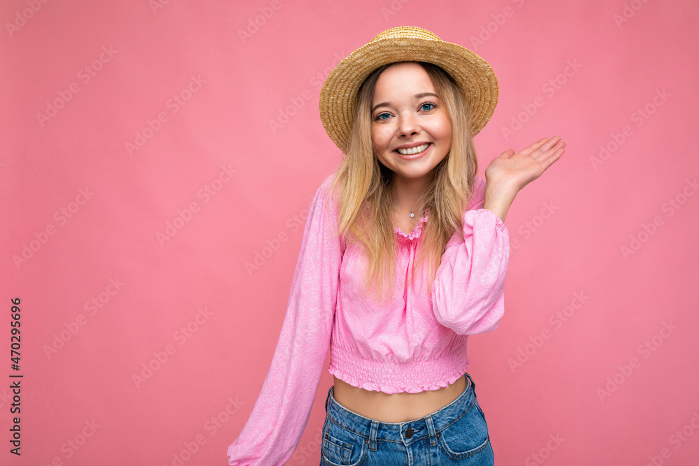 Young beautiful woman in stylish pink summer blouse and trendy straw hat. Positive female shows facial emotions. Funny model isolated on pink background with free space Young beautiful woman in stylish pink summer blouse and trendy straw hat. Positive female shows facial emotions. Funny model isolated on pink background with free space