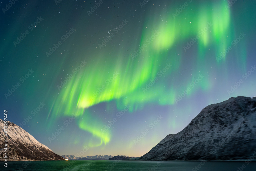 tanzende Nordlichter über Reinøya und Karlsøya. grün, gelb, pink Aurora Borealis im Ullsfjord, Troms, Norwegen. verschneite Berge auf den Inseln. sternenklarer Himmel über dem Postschiff.