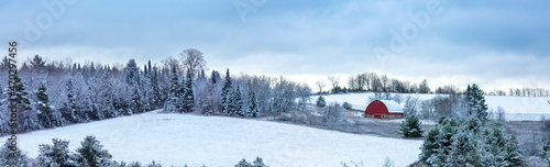 Old red barn next to a snow covered forest in a  Wisconsin