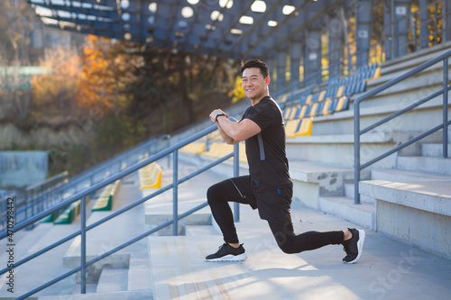 Male athlete trains in a backpack, asian fitness performs exercises outside the stadium in the morning
