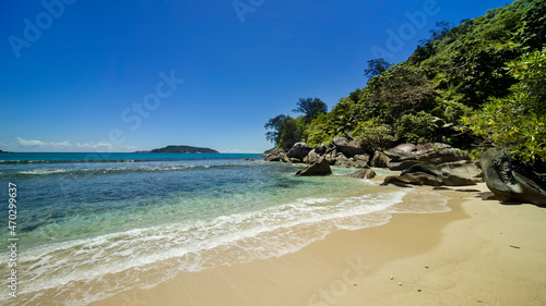 Seascape- turquoise wave runs along the light, untouched sand of the beach, rocks of unusual shape in the coastline.