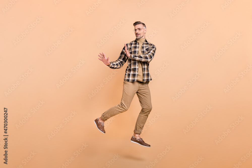 Full size photo of mature man jump demonstrate arms no stop symbol look empty space isolated over beige color background Full size photo of mature man jump demonstrate arms no stop symbol look empty space isolated over beige color background