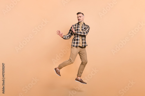 Full size photo of mature man jump demonstrate arms no stop symbol look empty space isolated over beige color background