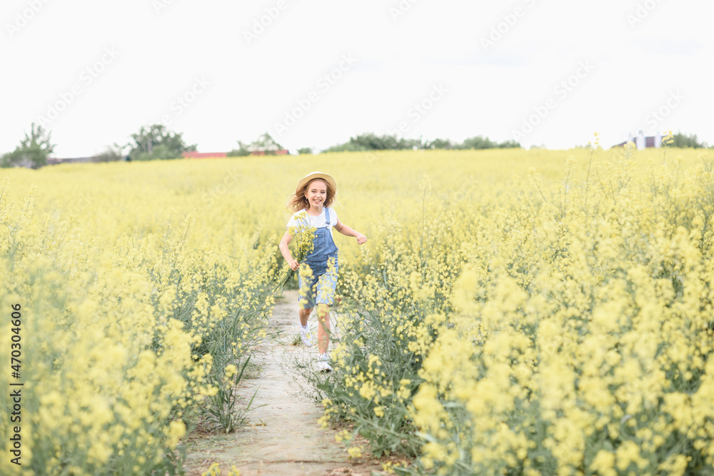 little girl in a rapeseed field holding flowers