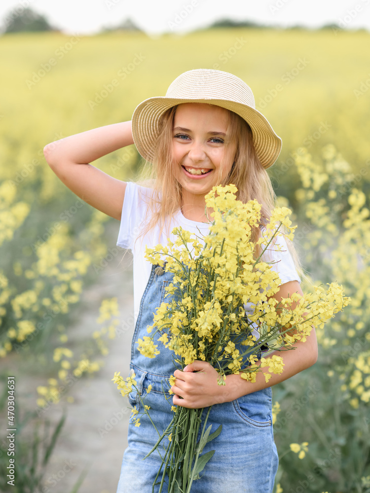 little girl in a rapeseed field holding flowers