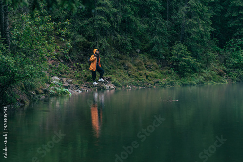 woman hiker in yellow raincoat at lake beach