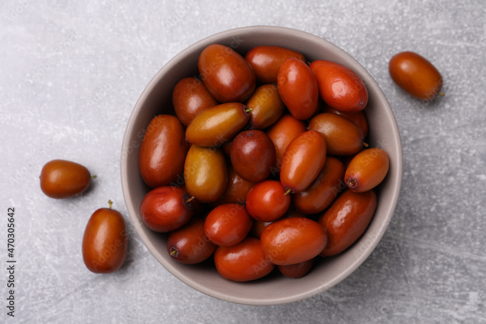 Fresh Ziziphus jujuba fruits with bowl on light table, flat lay Fresh Ziziphus jujuba fruits with bowl on light table, flat lay