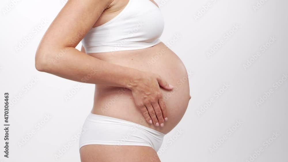 Young, happy and healthy pregnant woman on white background. Studio video. Baby expectation, pregnancy and motherhood concept. Young, happy and healthy pregnant woman on white background. Studio video. Baby expectation, pregnancy and motherhood concept.