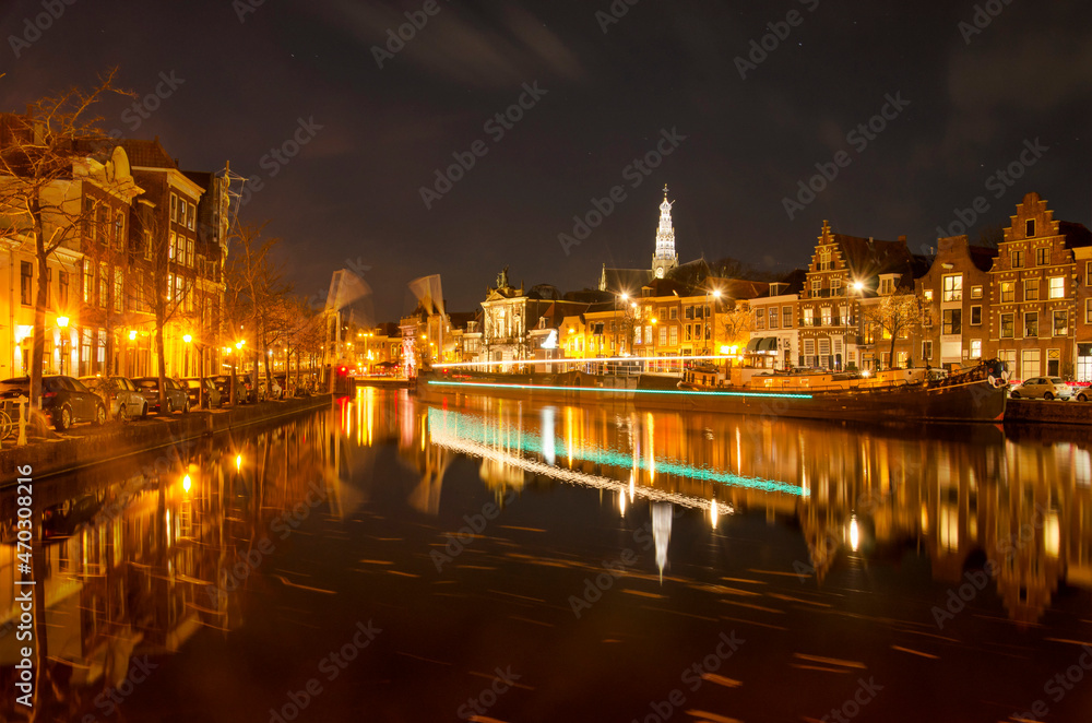 Haarlem, The Netherlands, November 19, 2021: view along Spaarne river at night with a lighttrail of a boat that just passed an opened drawbridge