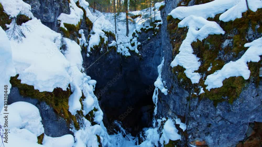 Crumbling ground covered with snow in winter coniferous forest. Landslip, landslide, slope failure, landform leading to underground cave, grotto in wooded area. Gully, gorge, crevice Crumbling ground covered with snow in winter coniferous forest. Landslip, landslide, slope failure, landform leading to underground cave, grotto in wooded area. Gully, gorge, crevice