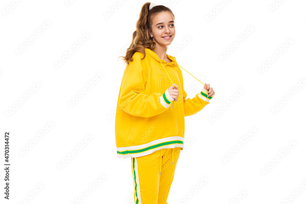 Photo of beautiful funny happy wonderful smiling cute girl with dark hair with ponytail in stylish yellow tracksuit with green stripes isolated on white background with free space for text