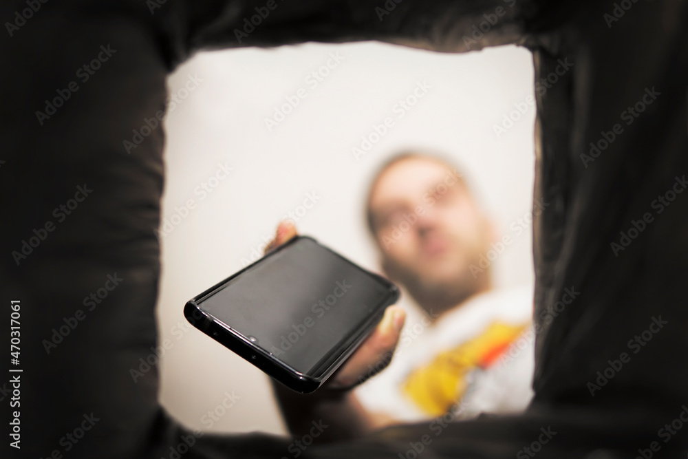 Foto man throws a non-working smartphone into a trash can