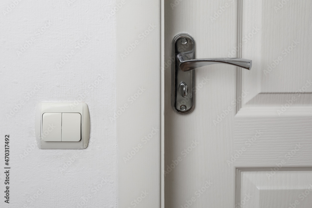 Modern light switch on white wall near door