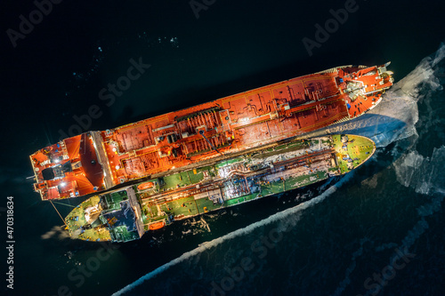 Two tankers at night, stand nearby in young ice. Shooting from air.