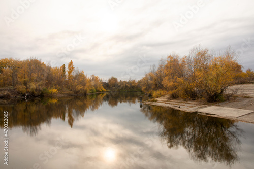 Autumn at pond with lonely fisherman