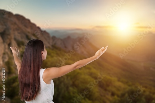Woman raised hands up on top of mountain and sunset background. Freedom, Pray, © BillionPhotos.com