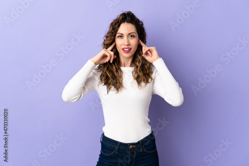 Young caucasian woman isolated on purple background frustrated and covering ears