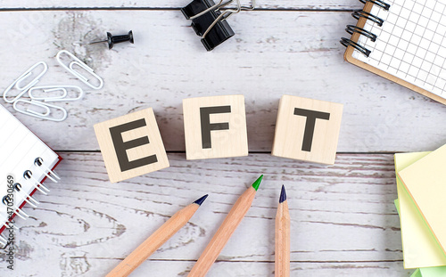 EFT text on wooden block with office tools on the wooden background photo