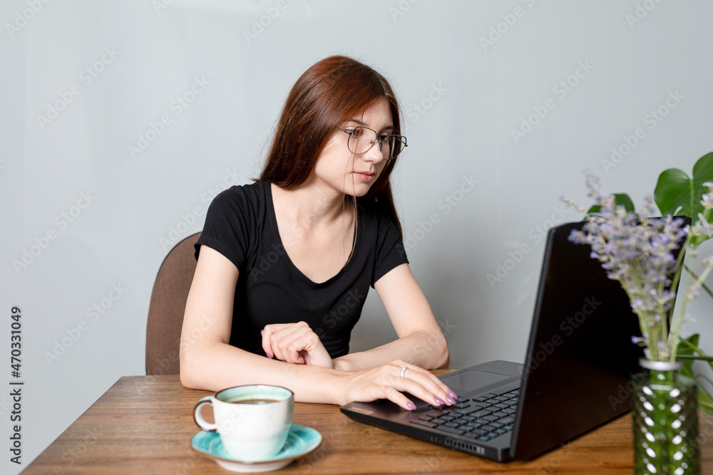 young woman is sitting in front of laptop, shopping on Internet, chatting with friends or just surfing web. cup of coffee on table young woman is sitting in front of laptop, shopping on Internet, chatting with friends or just surfing web. cup of coffee on table