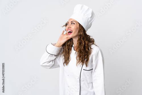 Young chef woman isolated on white background listening to something by putting hand on the ear photo