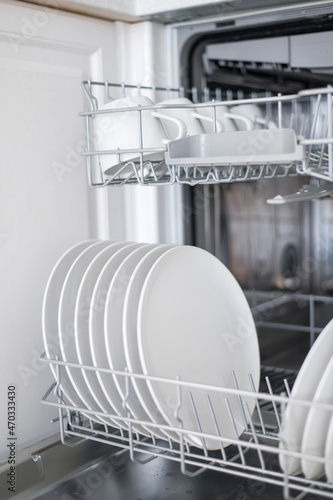 White flat plates are loaded into the dishwasher