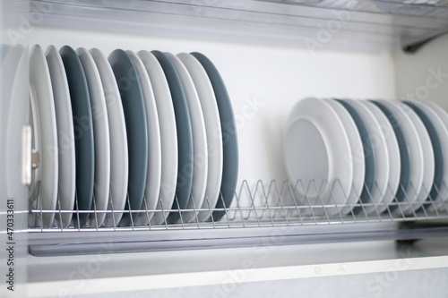 The plates are flat and deep stacked on the dryer in the kitchen