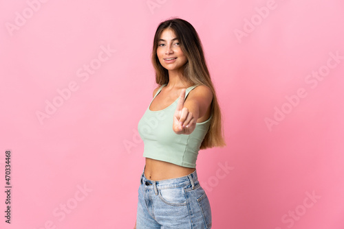 Young caucasian woman isolated on pink background showing and lifting a finger