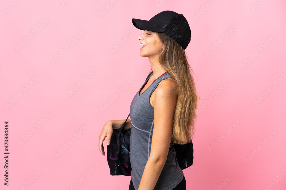 Young sport woman with sport bag isolated on pink background laughing in lateral position Young sport woman with sport bag isolated on pink background laughing in lateral position
