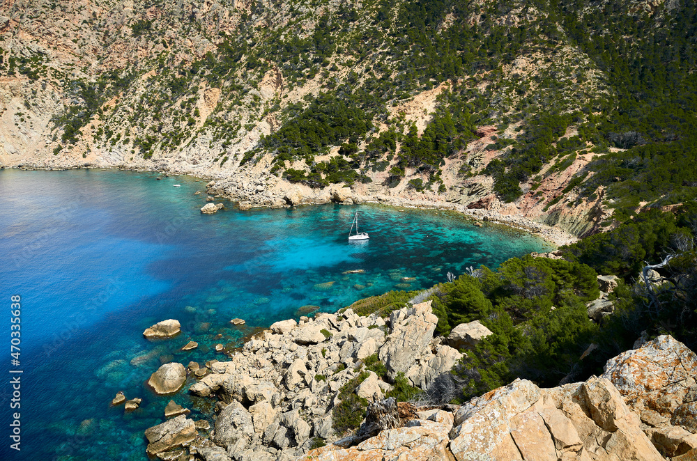 idyllic stone beach with turquoise water and a sailboat in majorca, spain 2