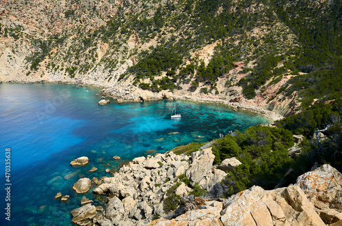 idyllic stone beach with turquoise water and a sailboat in majorca, spain 2