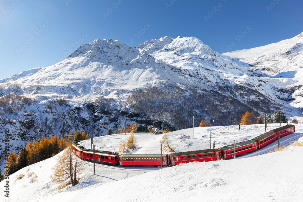 A red train is passing the train tracks with tight 180° curve at high Alp Grum. The Piz Palu peak is at the background. - obrazy, fototapety, plakaty 