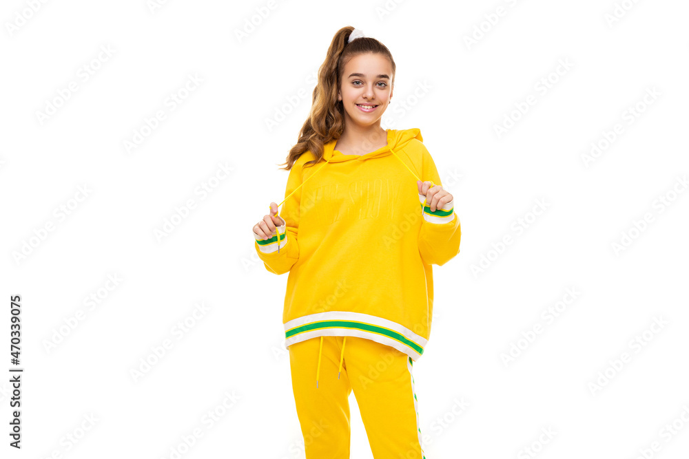 Beautiful funny happy wonderful smiling cute girl with dark hair with ponytail in stylish yellow tracksuit with green stripes isolated on white background with empty space for text Beautiful funny happy wonderful smiling cute girl with dark hair with ponytail in stylish yellow tracksuit with green stripes isolated on white background with empty space for text