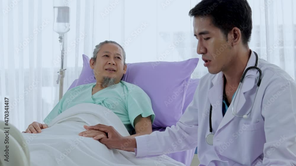 Asian male doctor talks and comforts an elderly patient at the bedside. Asian male doctor talks and comforts an elderly patient at the bedside.