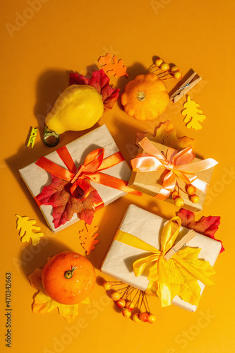 Gift concept in autumn colors. Wrapped boxes, festive fall decor, pumpkin, leaves, and berries