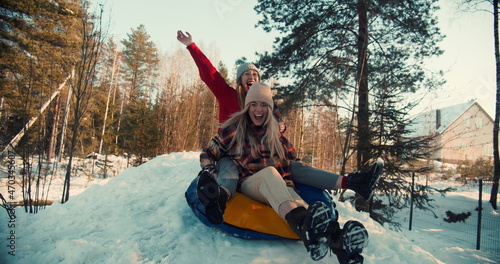 Fotografie Cinematic slow motion, two beautiful excited happy women sled towards camera on