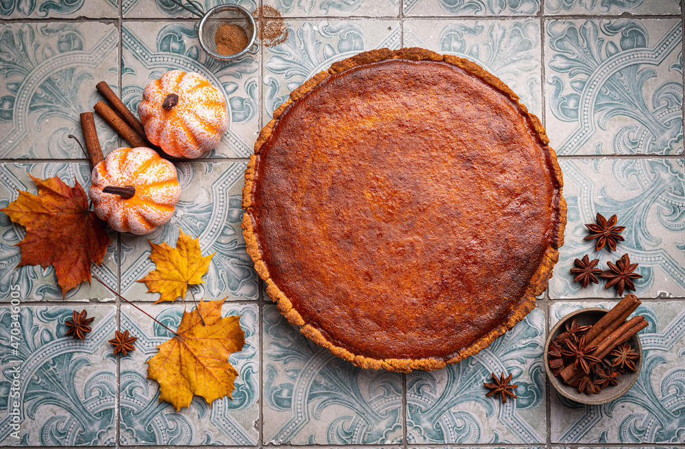 American pumpkin pie with cinnamon on tile background, top view American pumpkin pie with cinnamon on tile background, top view