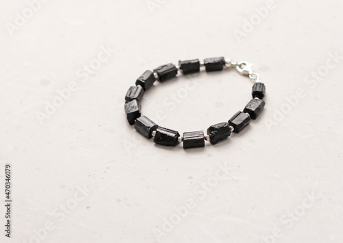 Black tourmaline, sherl bracelet. Bracelet made of stones on hand from natural stone Black tourmaline, sherl on light concrete modern background. Magic jewelry, lithotherapy and stone therapy photo