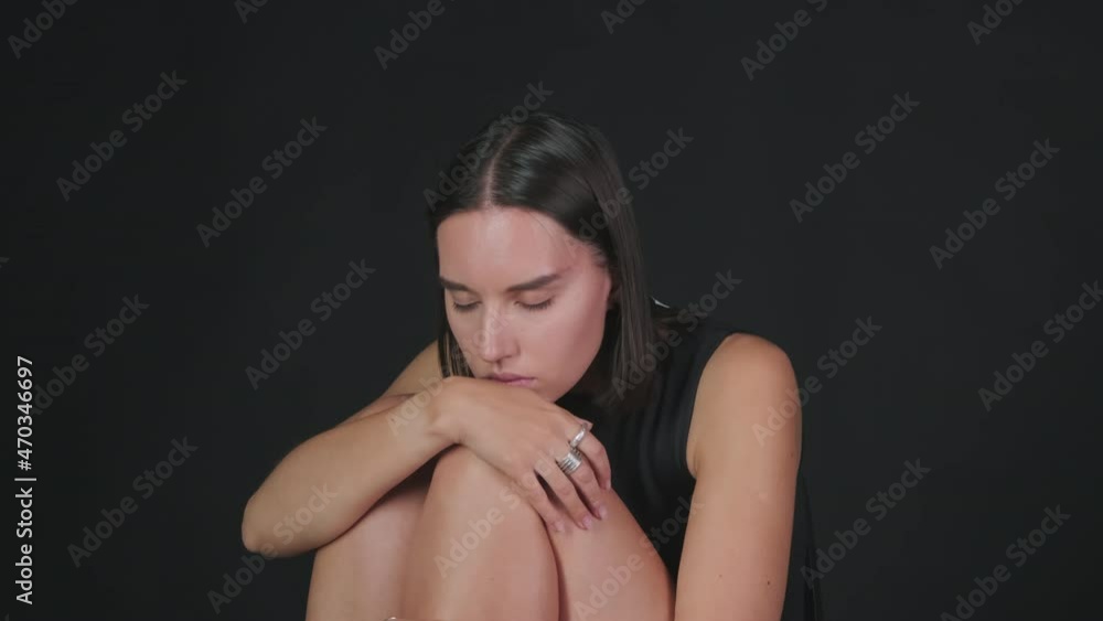 Tilt up shot of young woman wearing metal rings sitting with her eyes closed against black background Tilt up shot of young woman wearing metal rings sitting with her eyes closed against black background