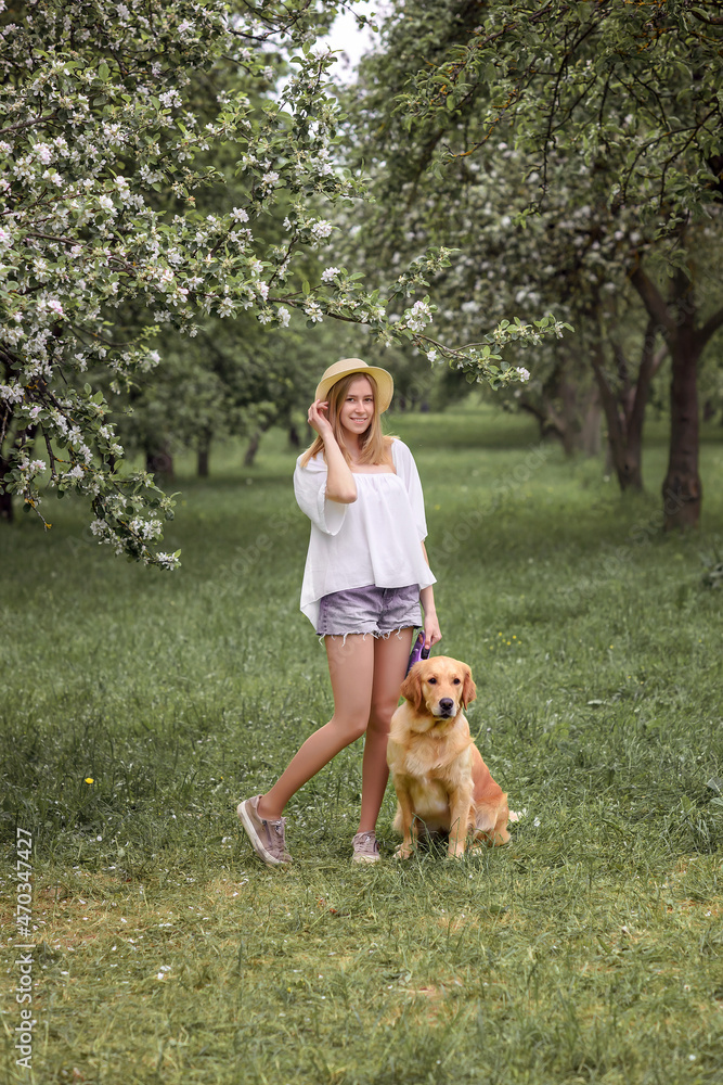 beautiful caucasian girl with golden retriever dog in blooming gardens