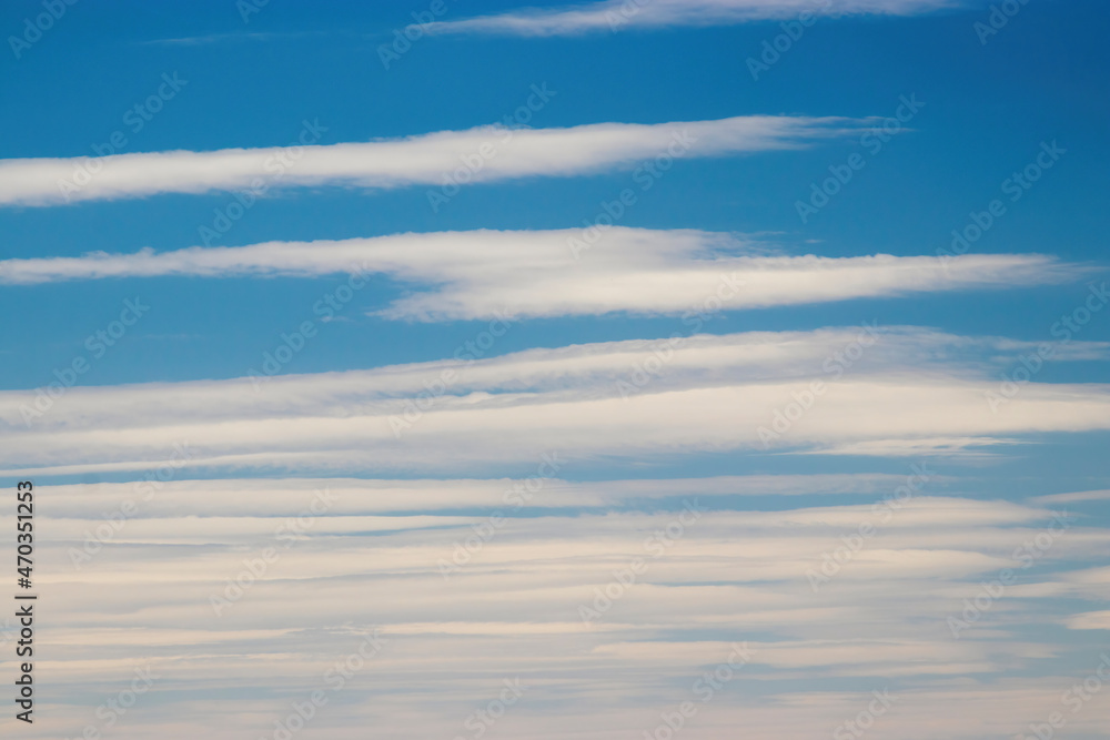 Background photo: blue sky and white clouds in the form of stripes. Blurred. High quality photo