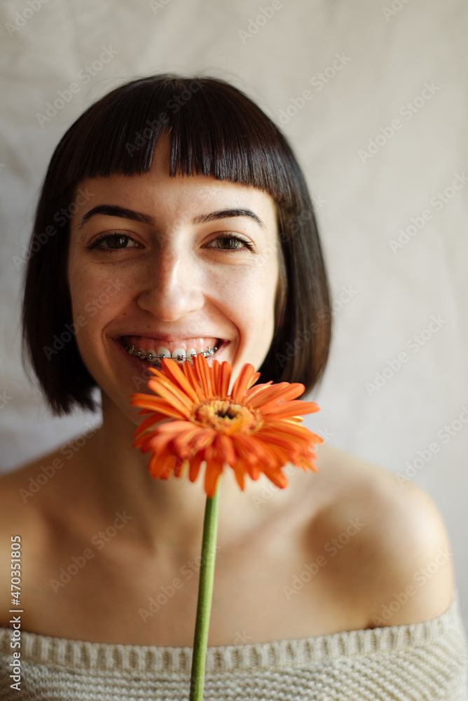 Studio portrait of a young beautiful woman with a flower in front of her face Studio portrait of a young beautiful woman with a flower in front of her face