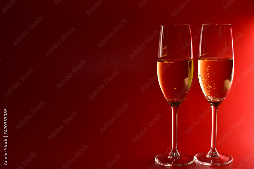 Elegant glasses with champagne on red background