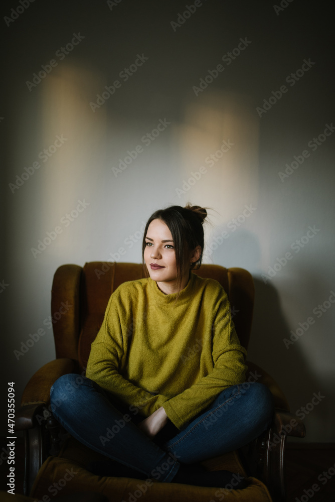 Obraz premium Portrait of a young woman sitting in armchair