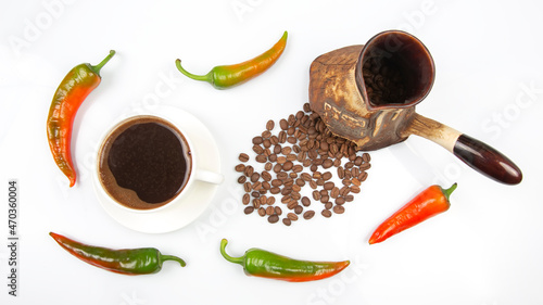 Freshly brewed hot black coffee in a white cup on a white plate next to a ceramic turkey with coffee beans. hot pepper