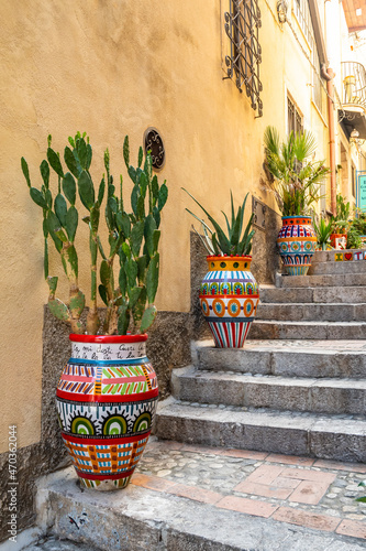 Alley with prickly pear cactus in decorated ceramic vases, Taormina, Italy