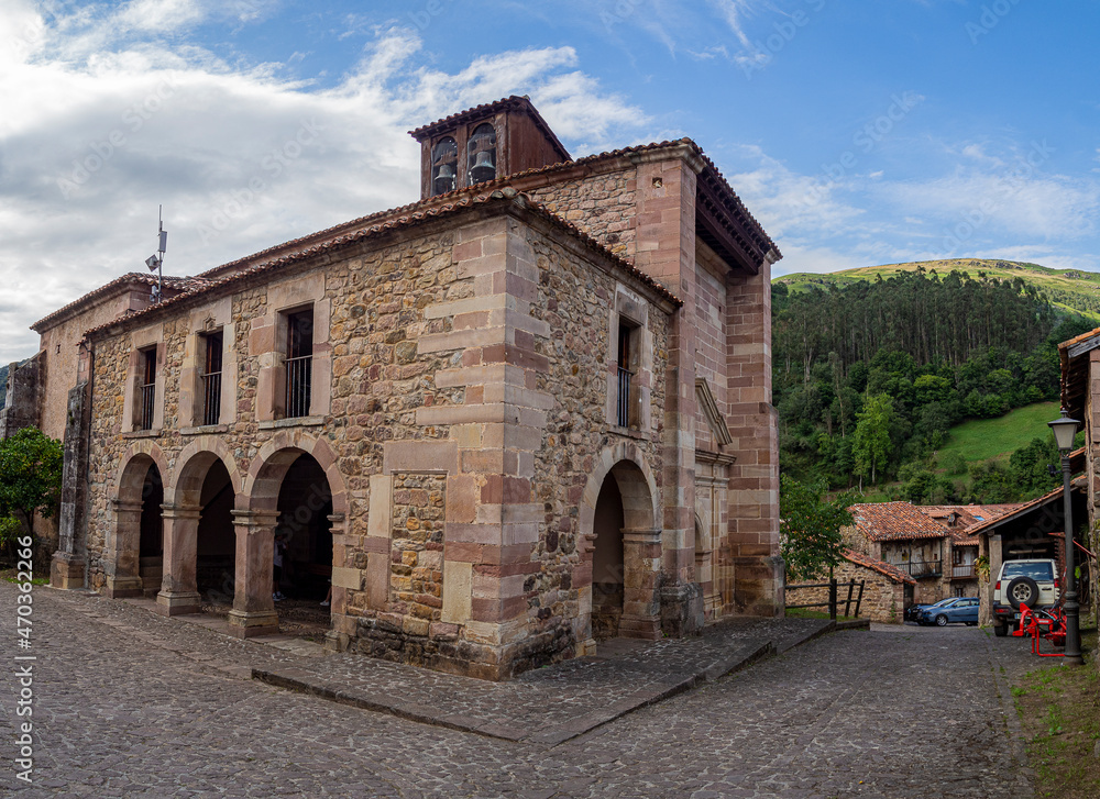 Vista de una iglesia antigua de piedra con arcos y un campanario en el pueblo de Carmona, en la Cantabria rural de España, verano de 2020