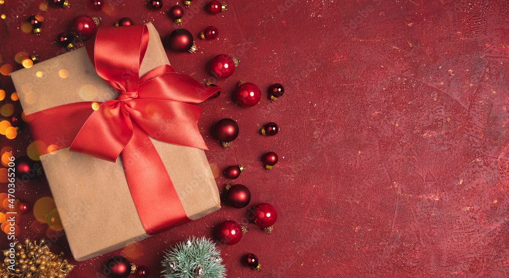Christmas gift box with red ribbon and red christmas balls on the red stone background Christmas gift box with red ribbon and red christmas balls on the red stone background